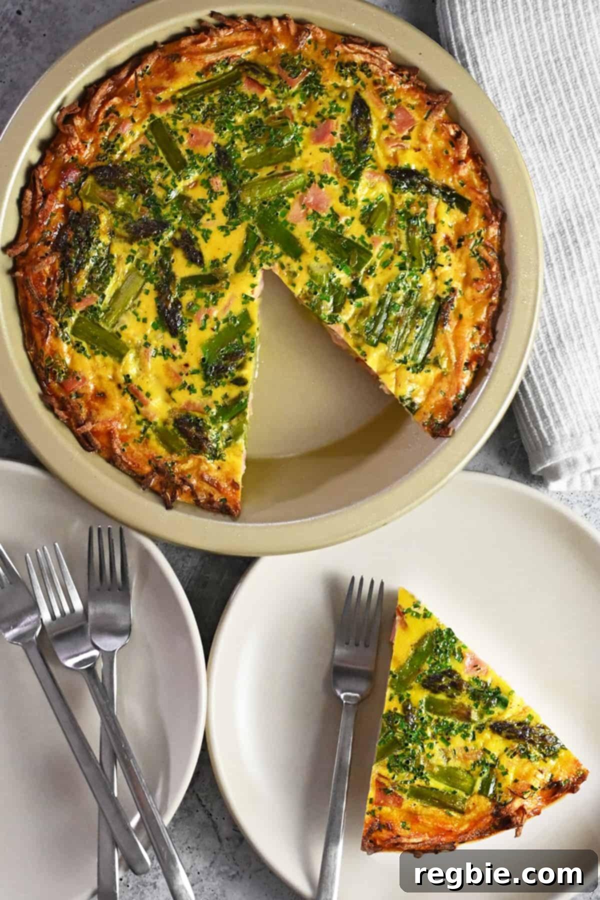 An appetizing overhead view of a paleo asparagus quiche with a slice removed and placed on a serving plate, ready to be enjoyed.