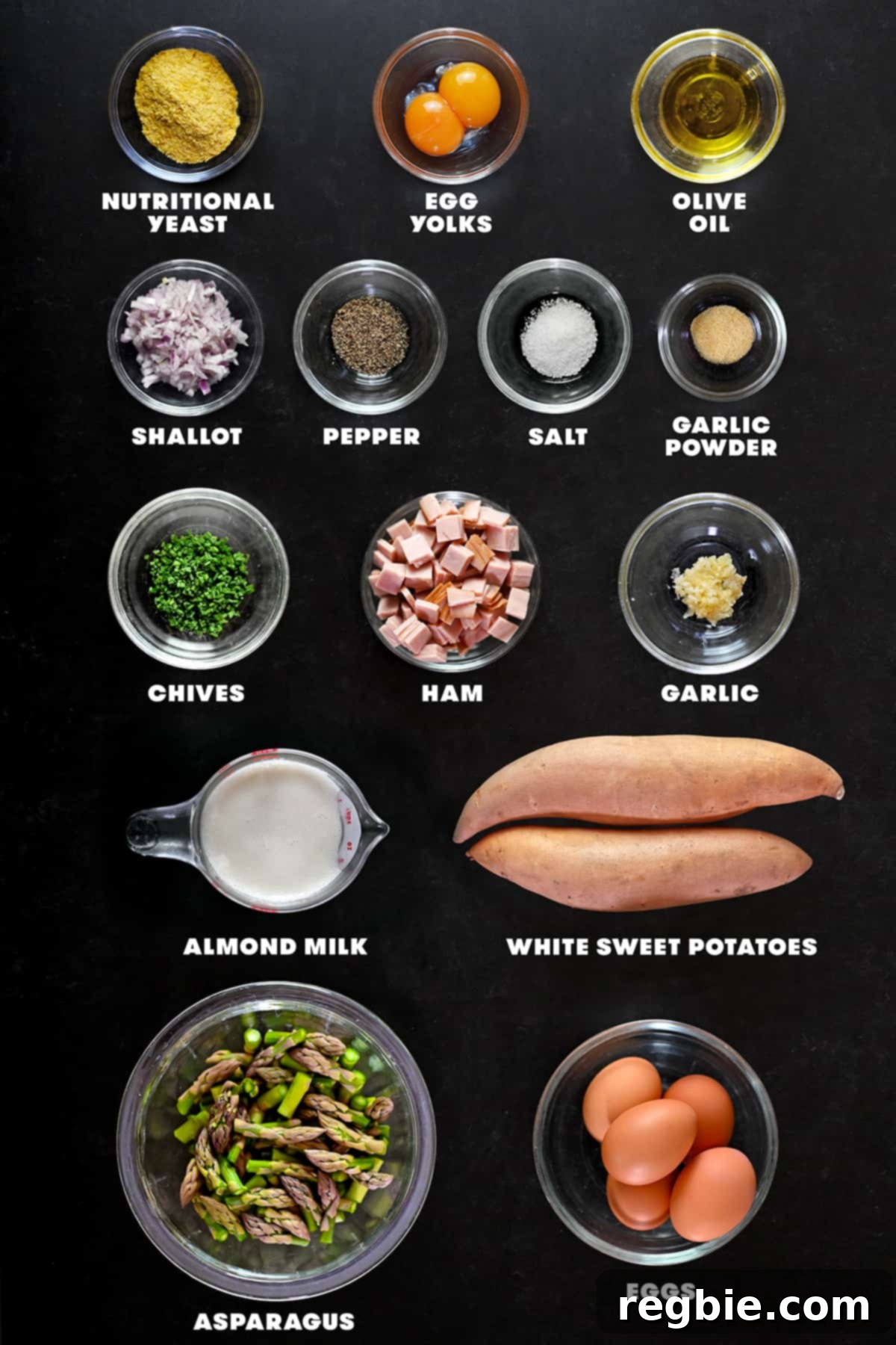 An artistic overhead shot displaying the vibrant raw ingredients laid out for preparing a paleo asparagus quiche, including fresh asparagus, eggs, and potatoes.