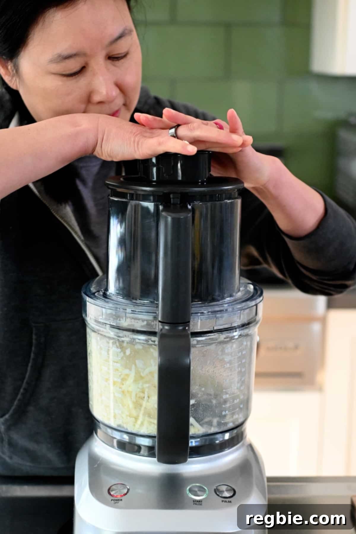 A person efficiently shredding a sweet potato using a food processor, demonstrating the initial step for the quiche crust.