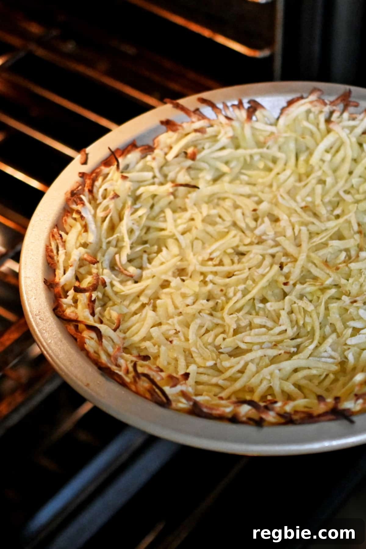 A freshly baked shredded potato crust, golden and firm, being removed from the oven and placed on a cooling rack.