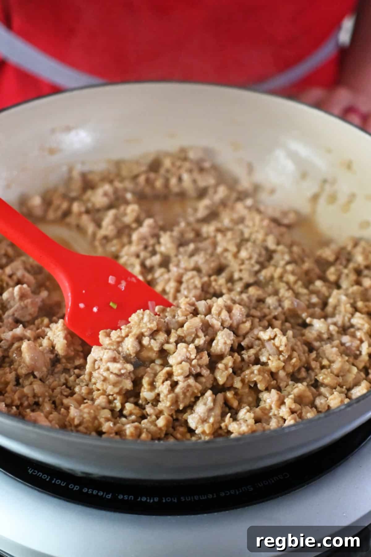 A skillet filled with ground chicken in a thickened brown sauce.