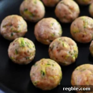 A black plate topped with paleo baked chicken meatballs made with shredded zucchini.