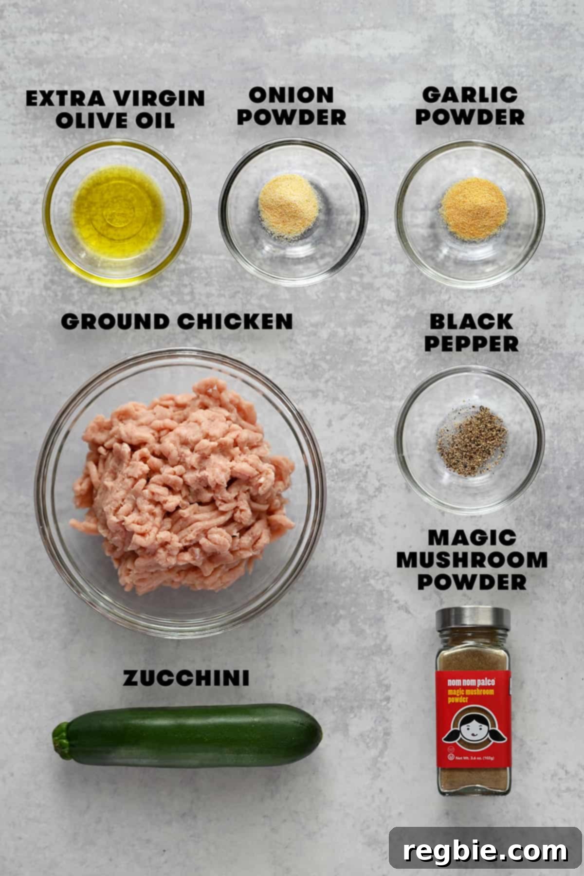 The raw ingredients meticulously laid out for preparing paleo and Whole30 compliant chicken meatballs, including ground chicken, shredded zucchini, olive oil, and various spices.