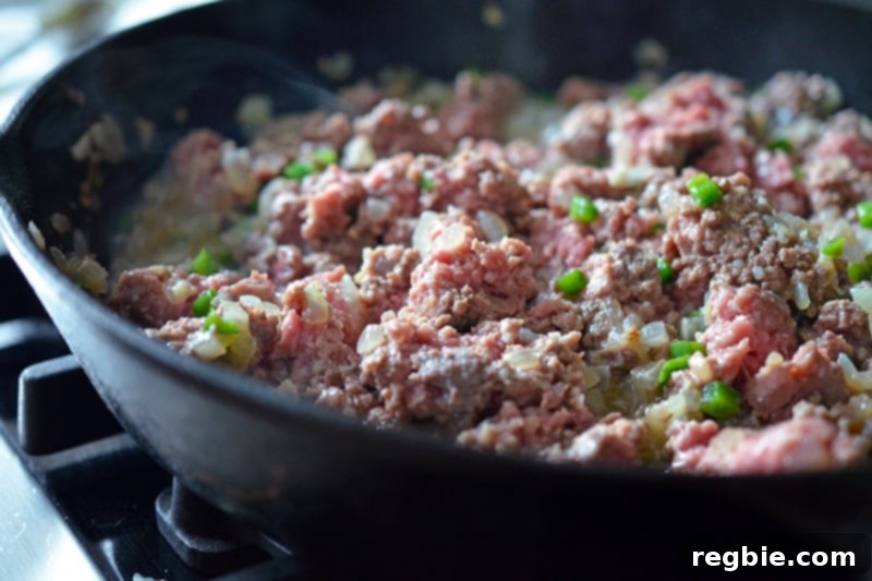 Aromatic Keema Samosa Platter 9 Ground meat being added to the pan with sautéed vegetables for deconstructed samosa.