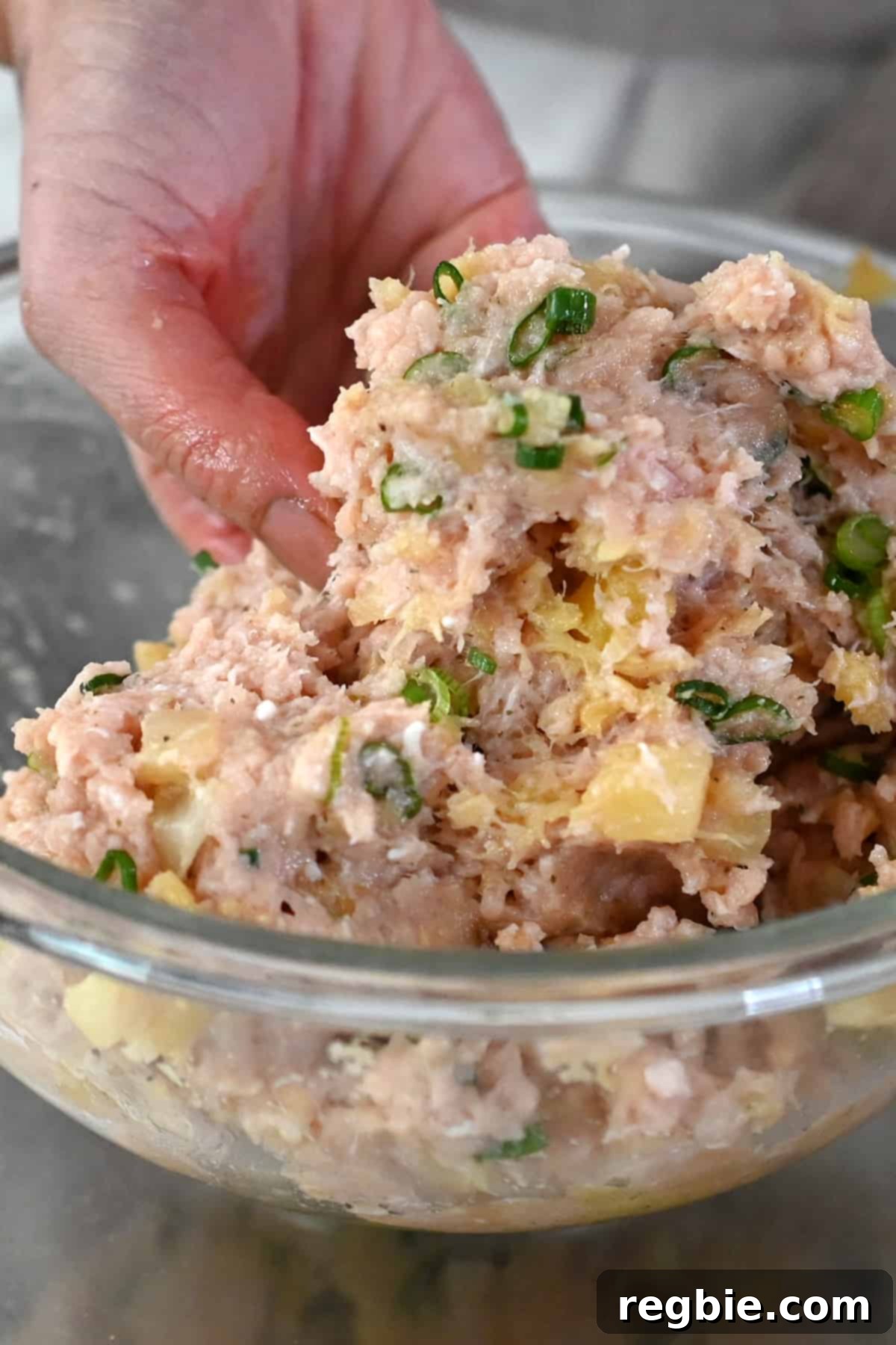 Mixing paleo teriyaki pineapple chicken meatball ingredients with clean hands.