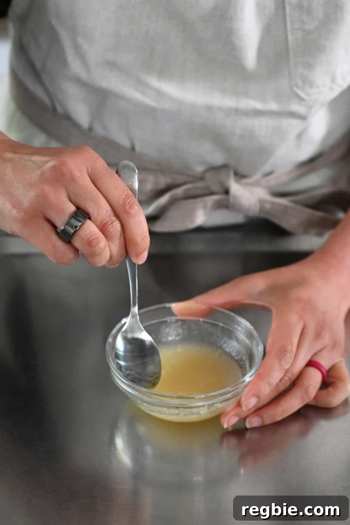 Stirring powdered gelatin and water in a small bowl, a crucial step to bloom the gelatin before incorporating it into the strawberry juice.