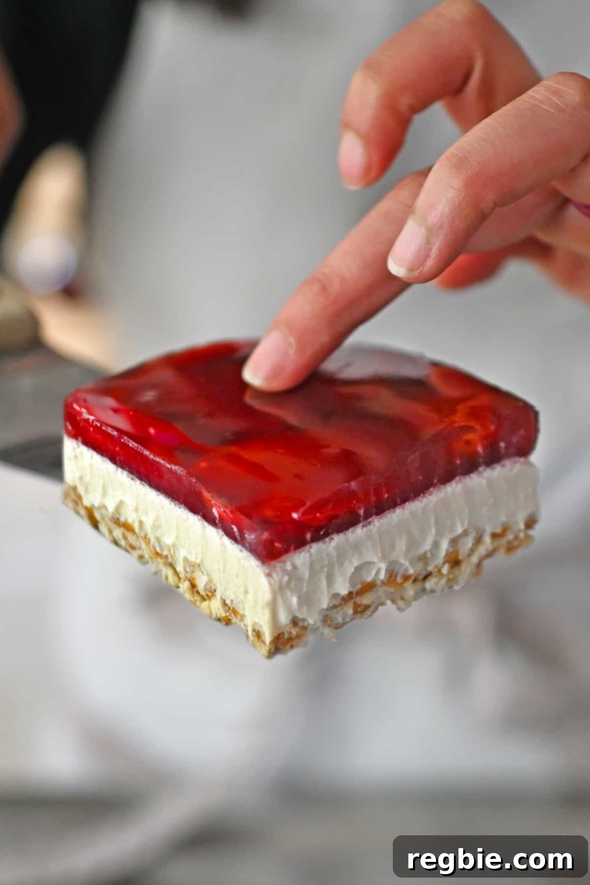A slice of grain-free, refined sugar-free, and dairy-free strawberry pretzel salad is gently being lifted with a spatula, ready to be enjoyed.