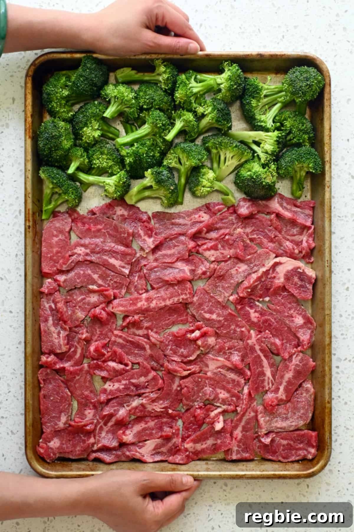 An overhead shot of the sheet pan, neatly arranged with seasoned beef and broccoli, perfectly ready to go into the oven for its first bake.
