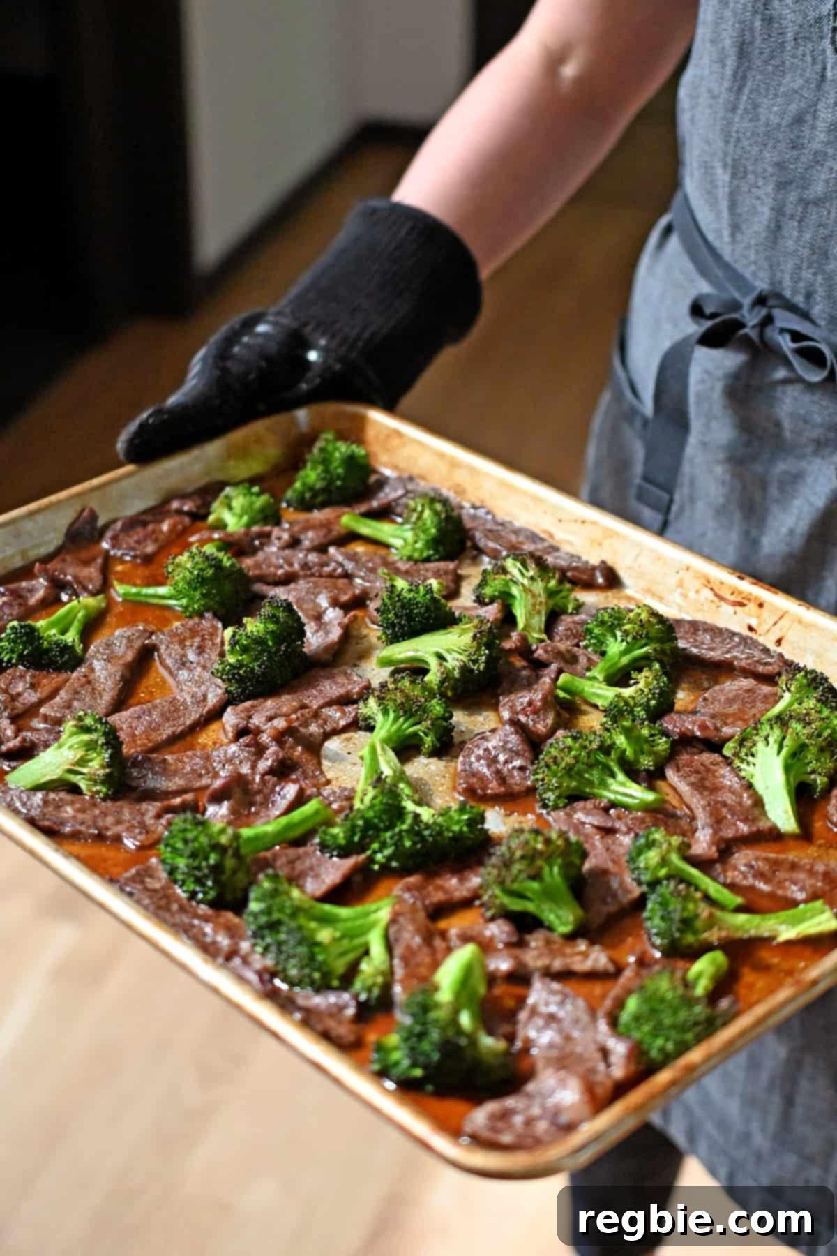 A perfectly cooked rimmed baking sheet filled with glistening Chinese beef and broccoli, just removed from the oven after broiling, showing delightful browning.