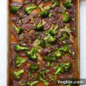 An overhead shot of sheet pan broccoli and beef topped with sliced green onions and toasted sesame seeds.