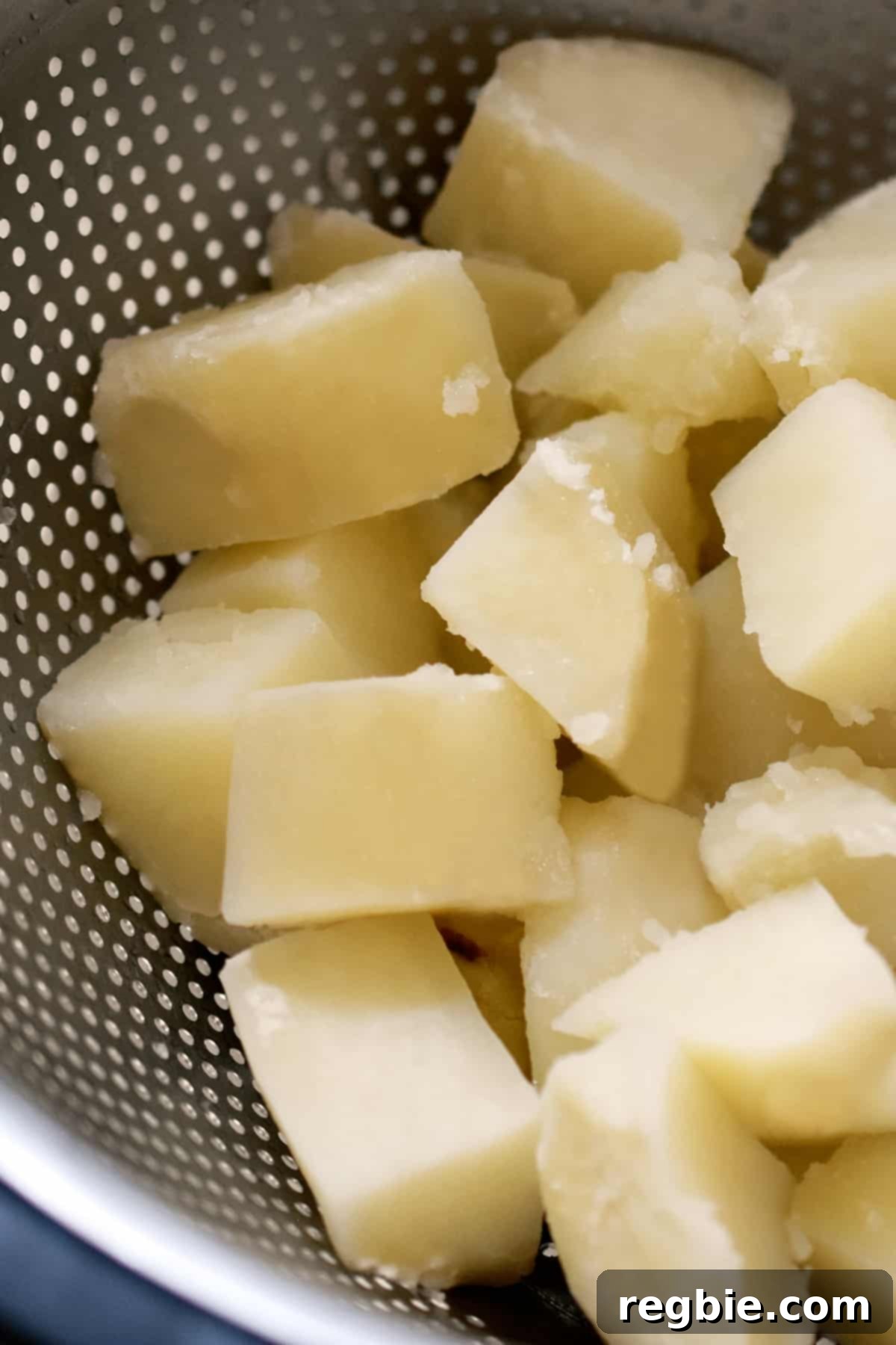 Boiled russet potato cubes in a colander, cooling down after cooking.