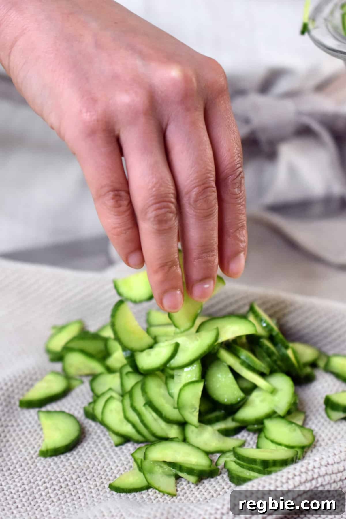 Placing salted thinly sliced Persian cucumbers onto a clean kitchen towel, preparing to squeeze out liquid.