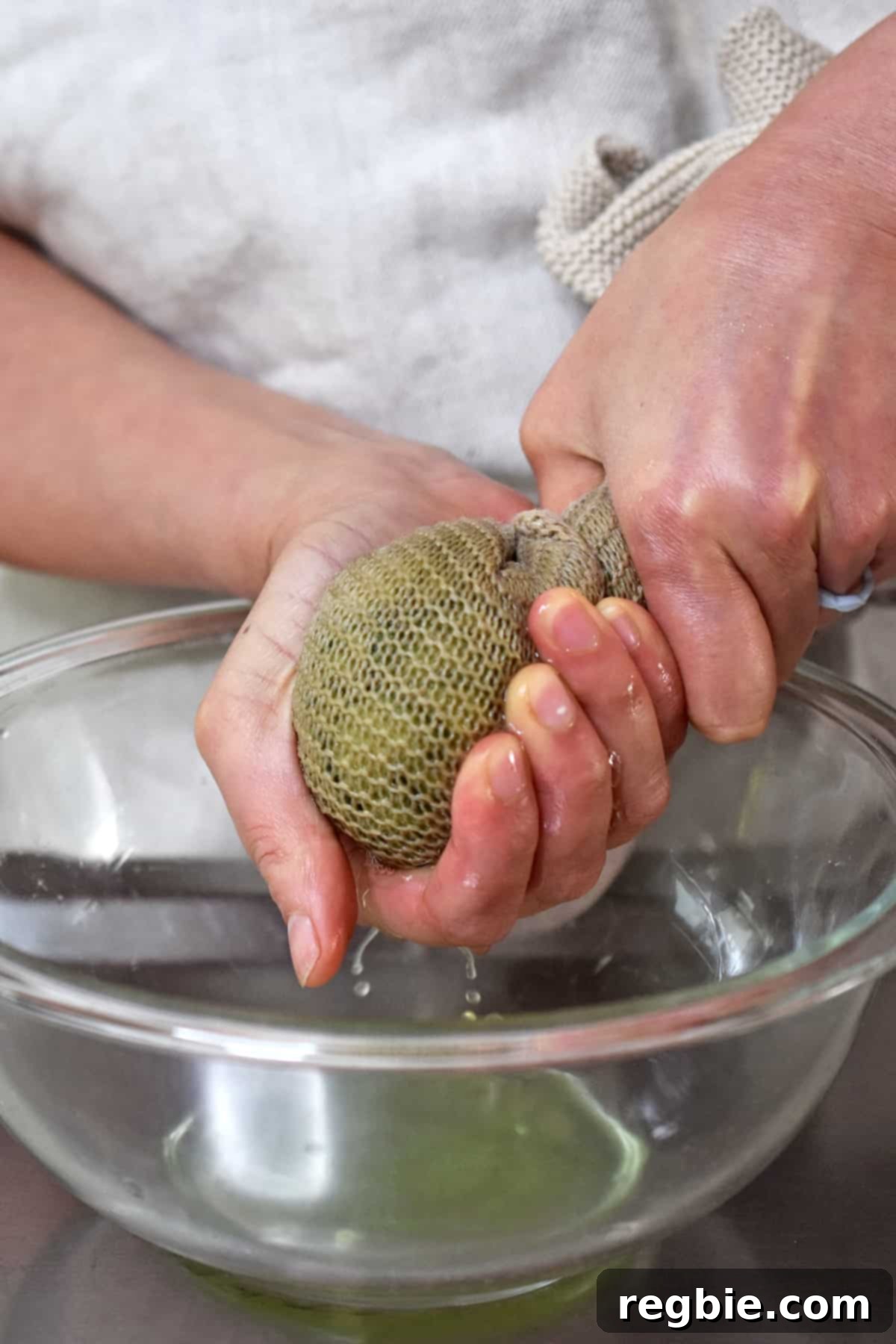 Squeezing the excess liquid out of salted cucumbers wrapped in a kitchen towel, demonstrating a key step for crunchy salad.