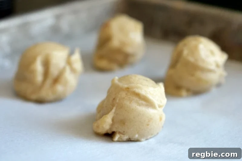 Guilt-Free Chunky Monkey Nice Cream Bonbons 9 A tantalizing closeup of small, perfectly formed scoops of paleo banana nice cream, arranged neatly on a parchment-lined baking sheet, awaiting their final transformation.