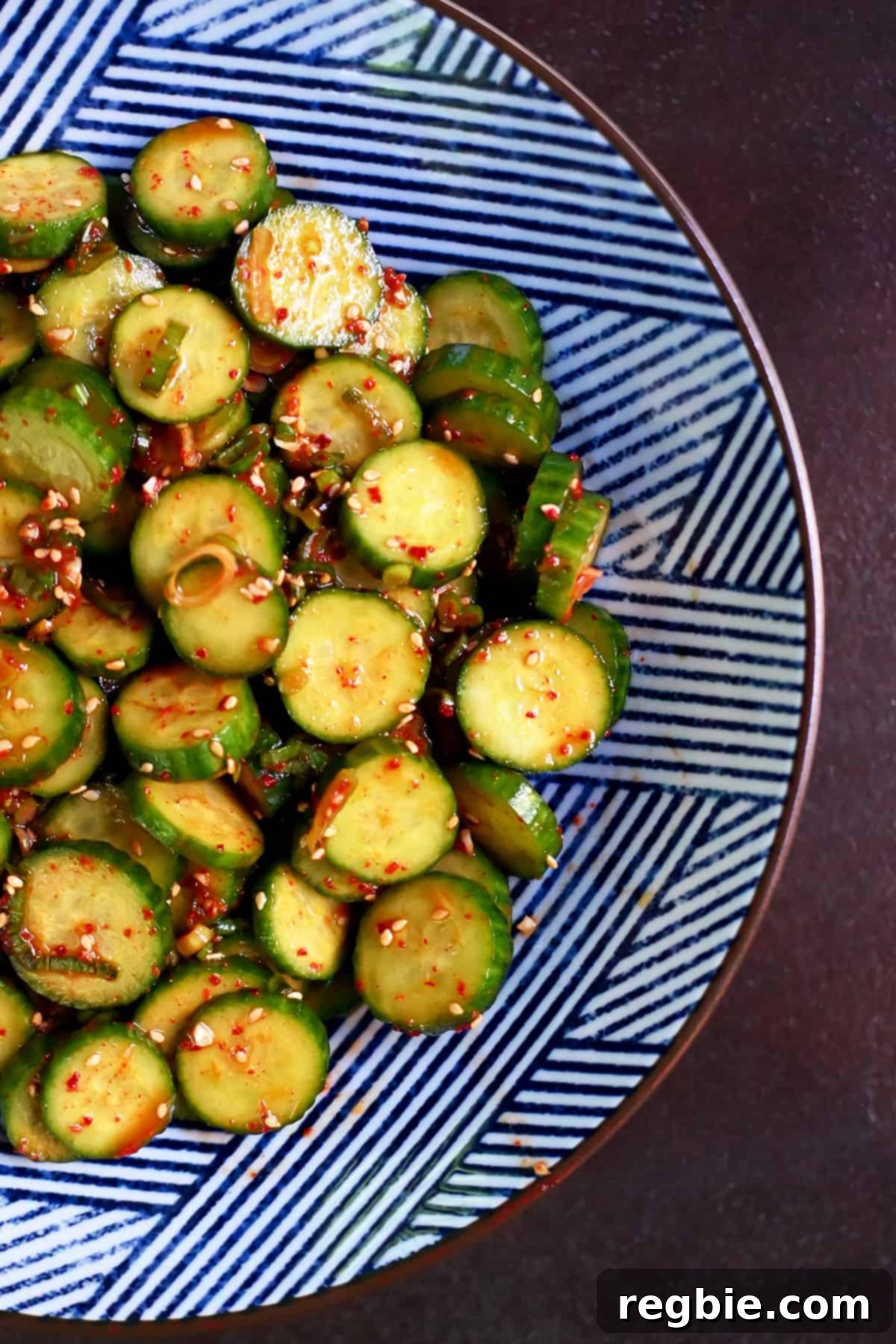 An inviting overhead shot of a beautifully presented blue and white serving bowl, showcasing a freshly made paleo and gluten-free Korean cucumber salad.