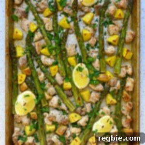 An overhead shot of Greek sheet pan chicken with asparagus, chicken, and potatoes topped with Italian parsley.