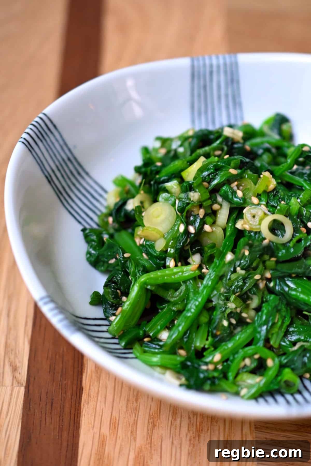 A captivating side shot of a beautiful white and blue serving bowl, artfully filled with the vibrant and delicious Korean spinach side dish, ready to be enjoyed.