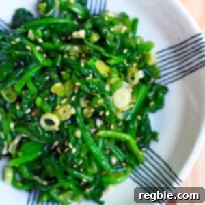 An overhead shot of a white and blue serving bowl filled with Korean spinach side dish.