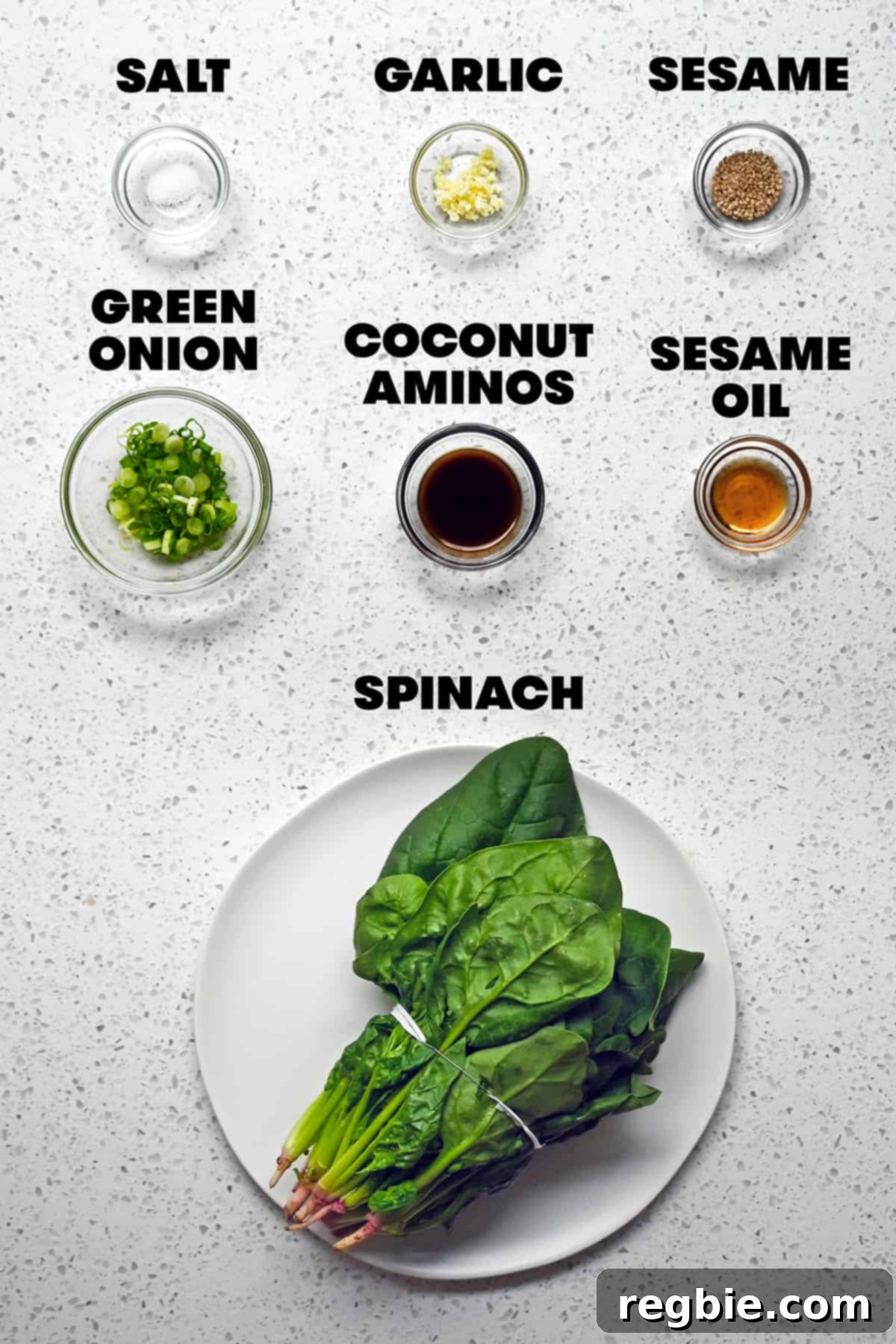 An overhead shot displaying the raw, fresh ingredients meticulously laid out to prepare the Korean spinach side dish, sigeumchi namul.