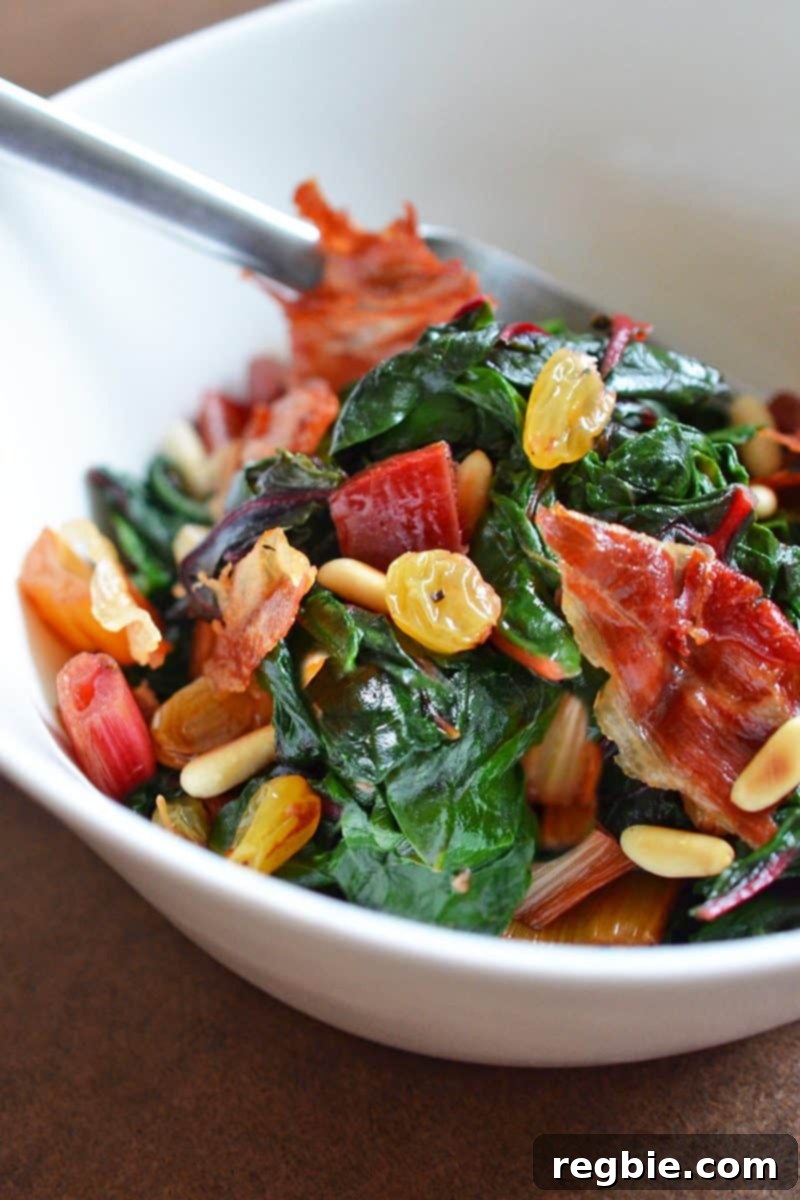 A beautifully plated Swiss chard salad with raisins, pine nuts, and crispy prosciutto in a rustic bowl, ready to be enjoyed.