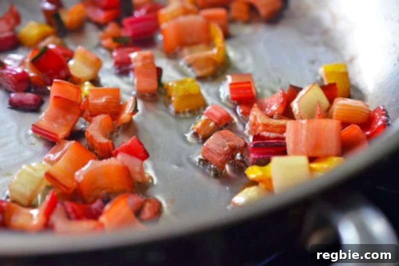 The Swiss chard stems are actively sautéing in the pan, becoming tender and slightly caramelized as they cook down.