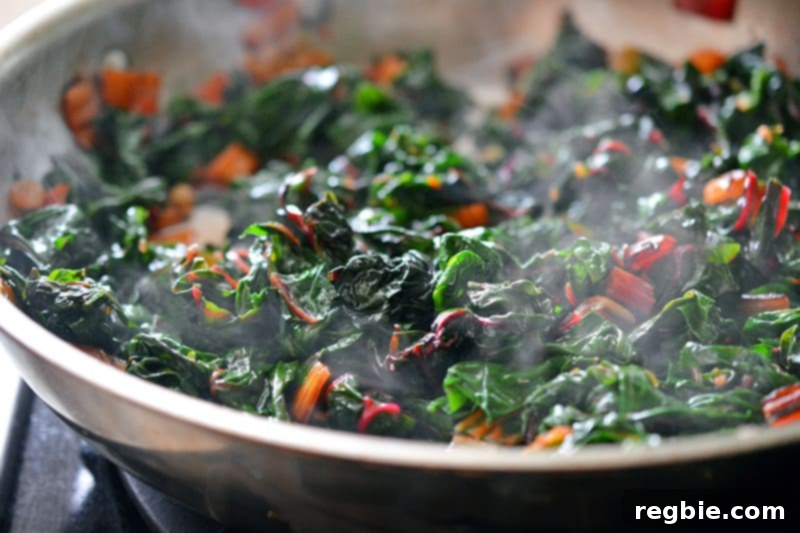 The Swiss chard and raisins are being stirred together in the covered pan, allowing all the ingredients to combine and cook further to tender perfection.