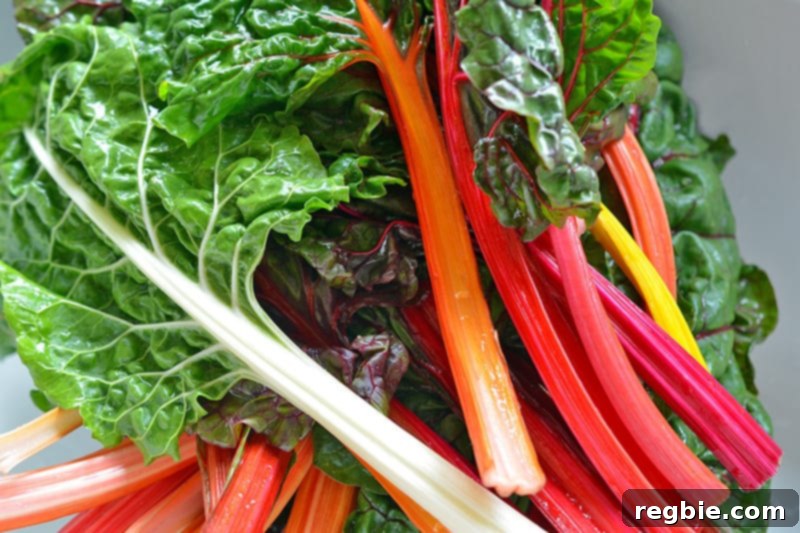 A close-up shot of a generous pile of freshly washed rainbow Swiss chard, its colorful stems glistening, ready for preparation.