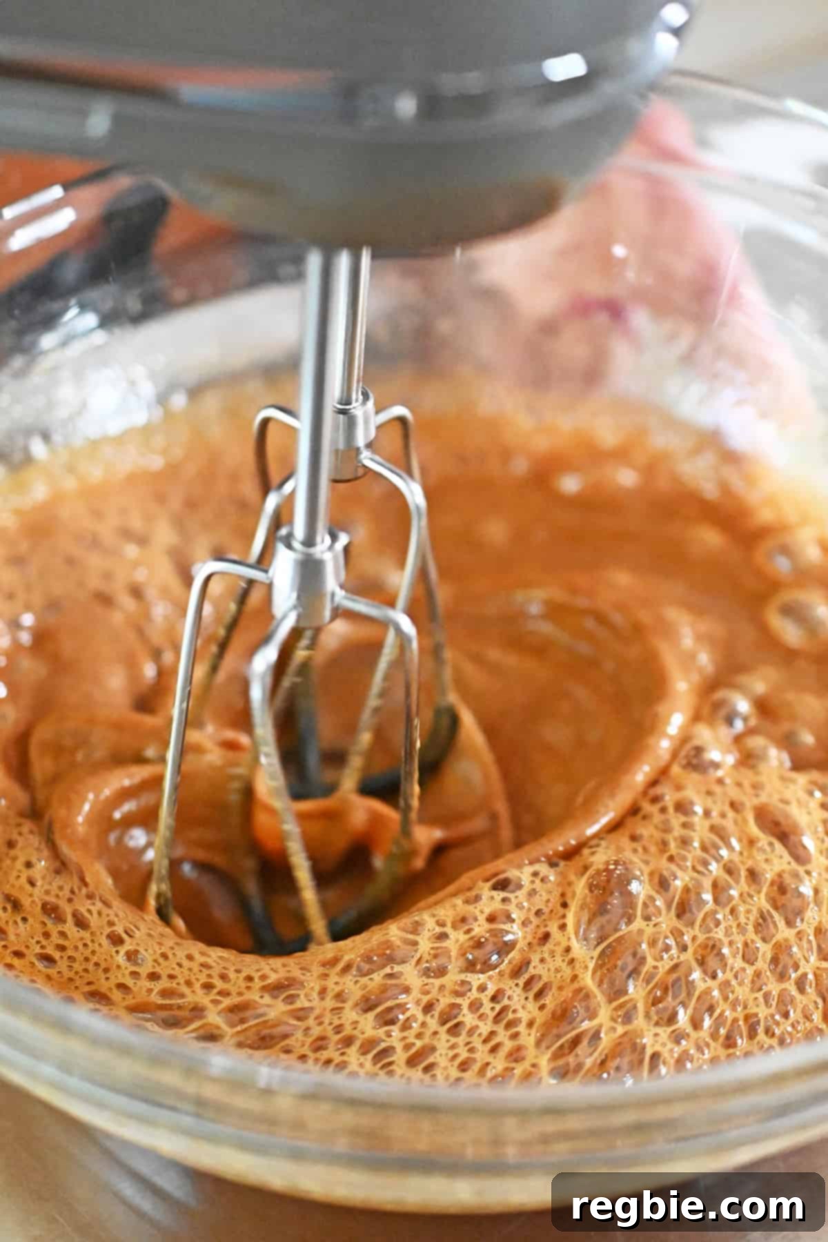 Blending the eggs and coconut sugar until it is frothy and a lighter brown color, indicating proper emulsification.