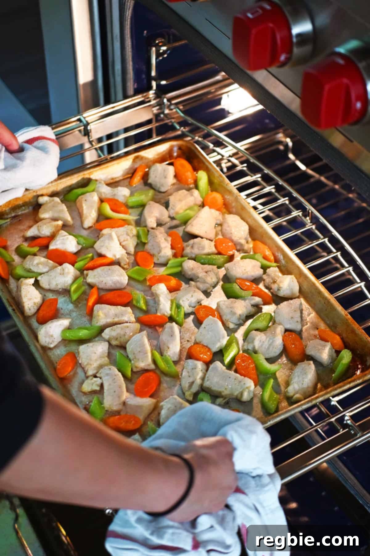 Sheet Pan Cashew Chicken: Paleo & Whole30 Perfection 13 A sheet pan, laden with perfectly cooked chicken breast cubes, tender sliced carrots, and celery, is being carefully removed from the oven.