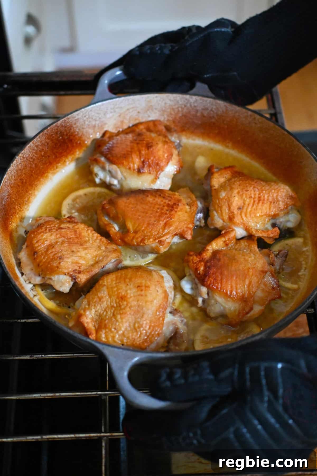 Removing a skillet filled with lemon garlic chicken thighs from the oven.