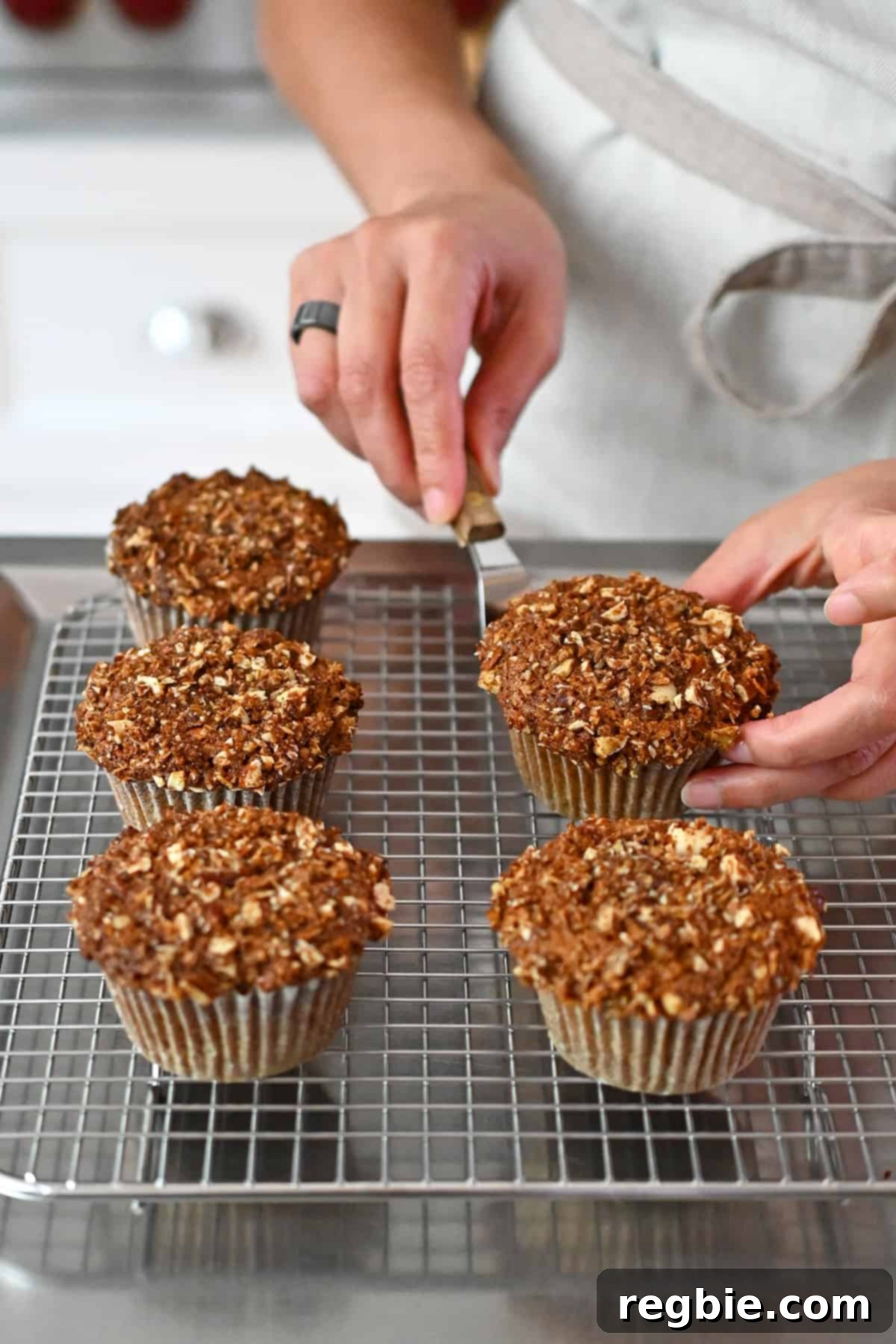 Placing the freshly baked apple muffins on a wire rack to cool completely.