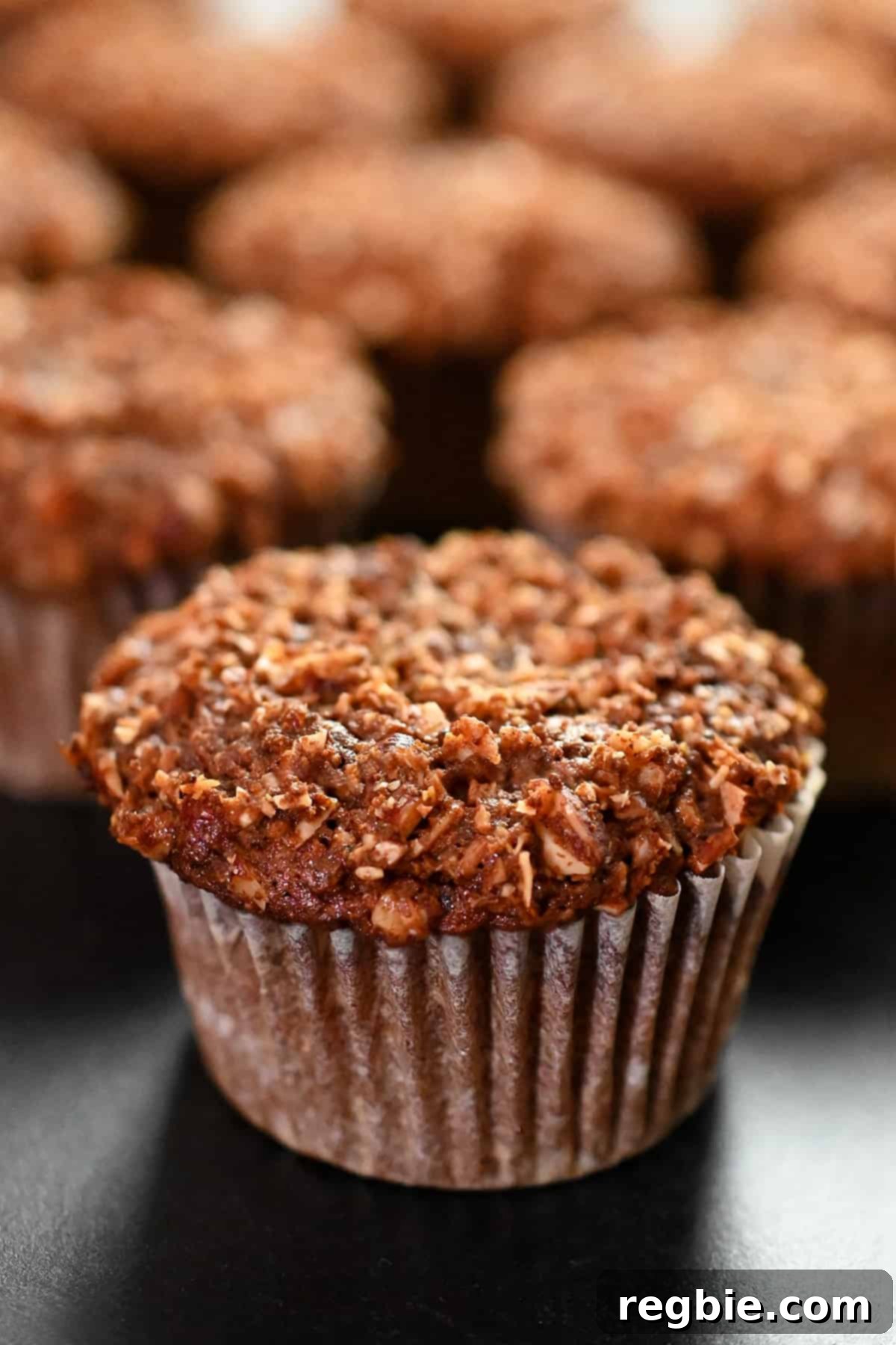 A closeup side view of paleo and gluten free apple muffins on a black background, highlighting their delicious appearance.