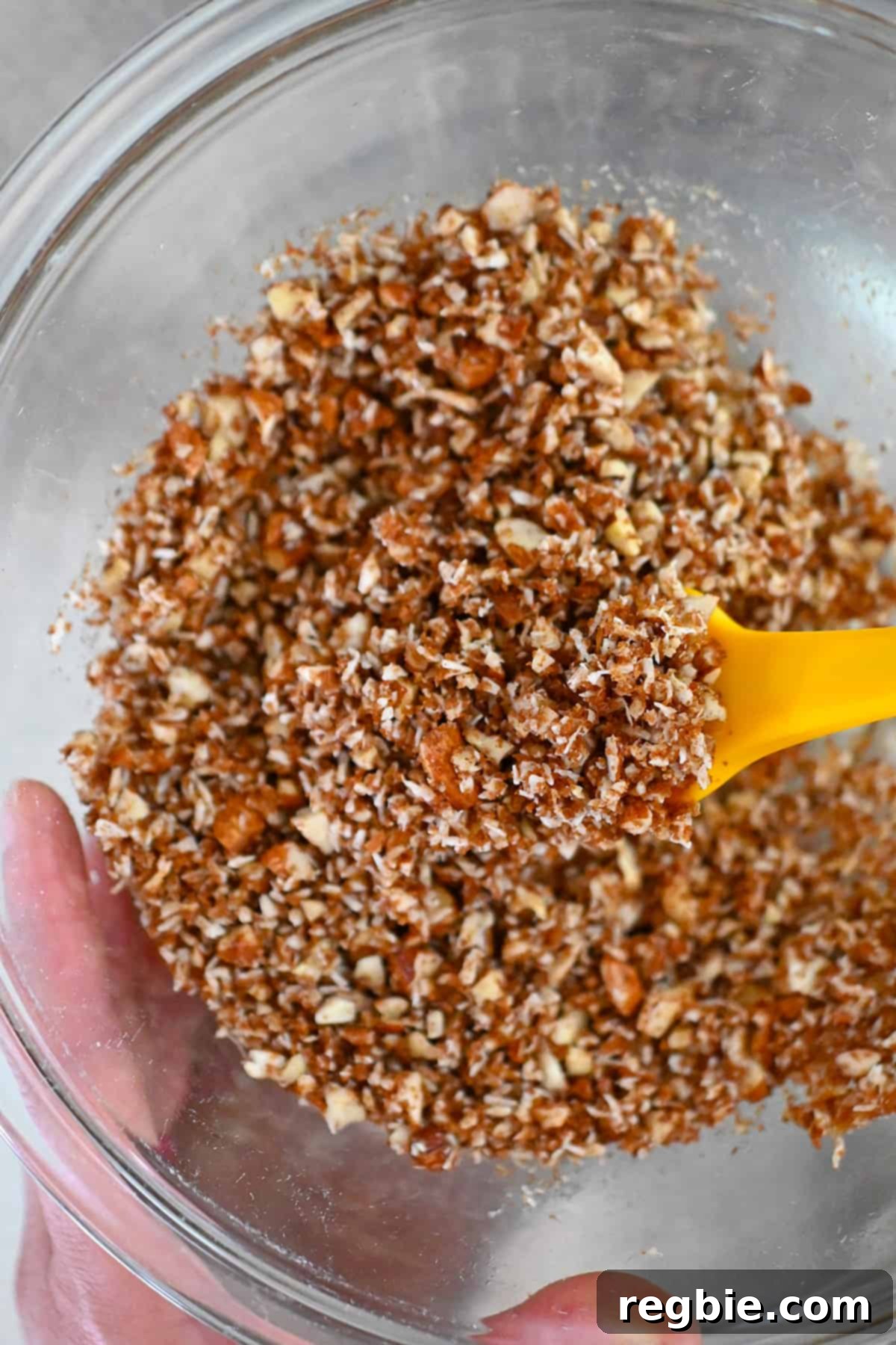 Mixing the paleo topping for apple muffins with melted coconut oil in a large glass mixing bowl until well combined.
