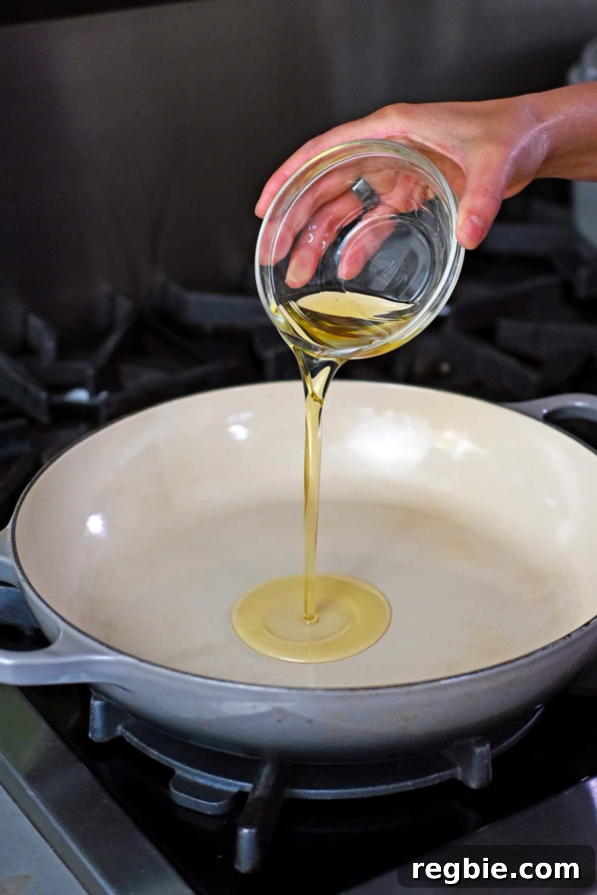 Pouring avocado oil into a large enameled cast iron skillet, ready for stir-frying.
