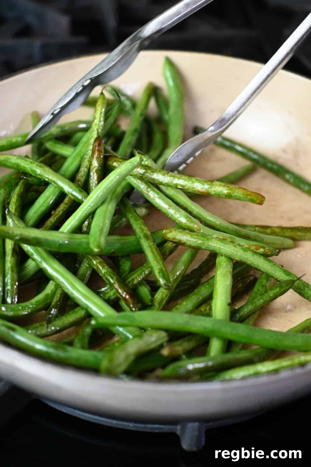 A close-up view of the blistered and perfectly stir-fried green beans in an enameled cast iron skillet.