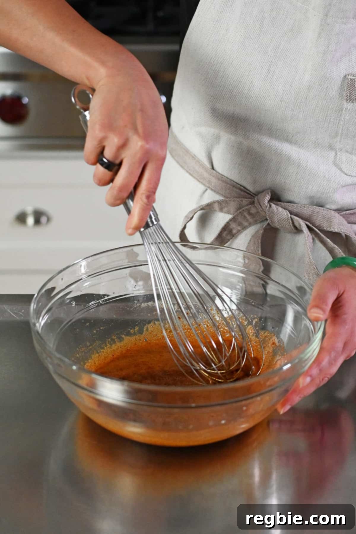 An action shot of whisking together the frothy whipped raw egg whites and the paleo spice blend in a bowl, creating a uniform coating.
