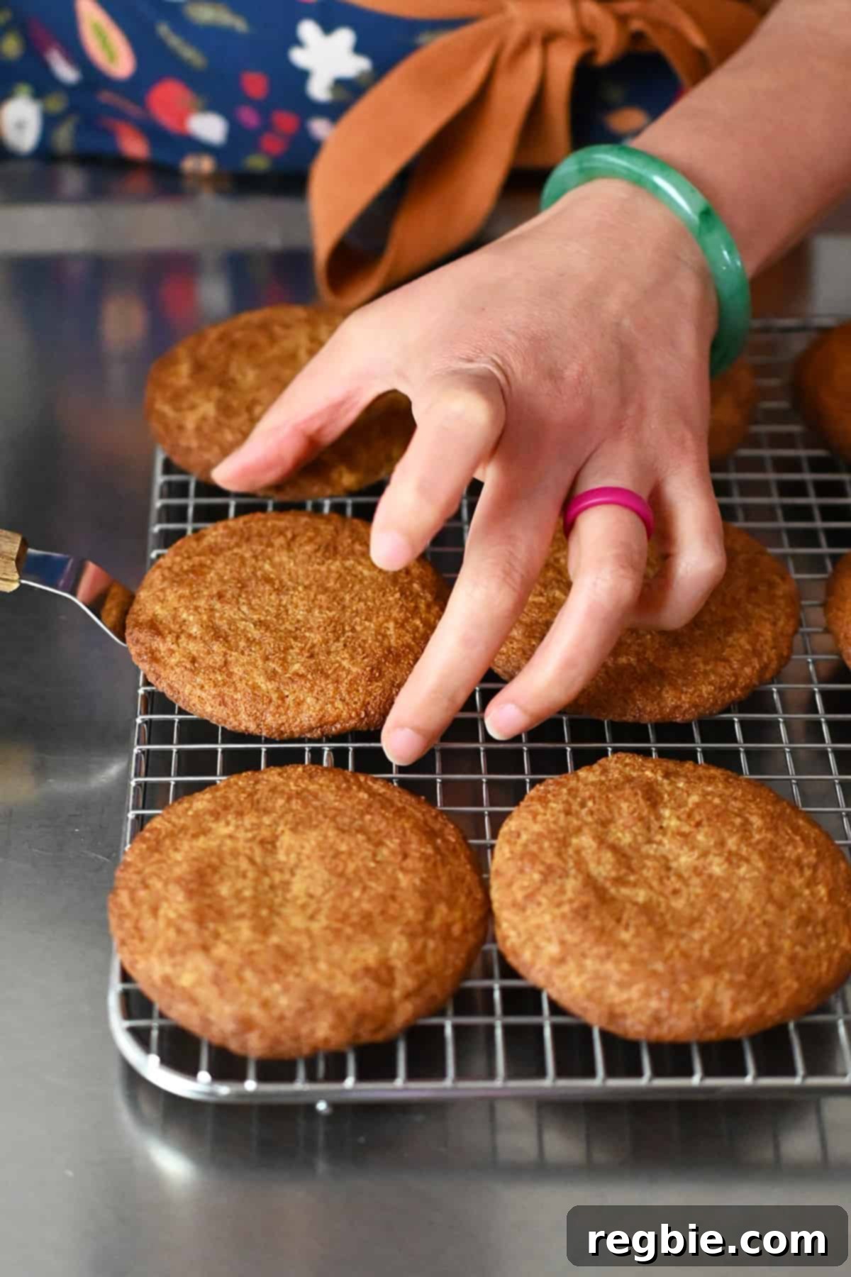 Transferring freshly baked snickerdoodles to a wire cooling rack using a small offset spatula.