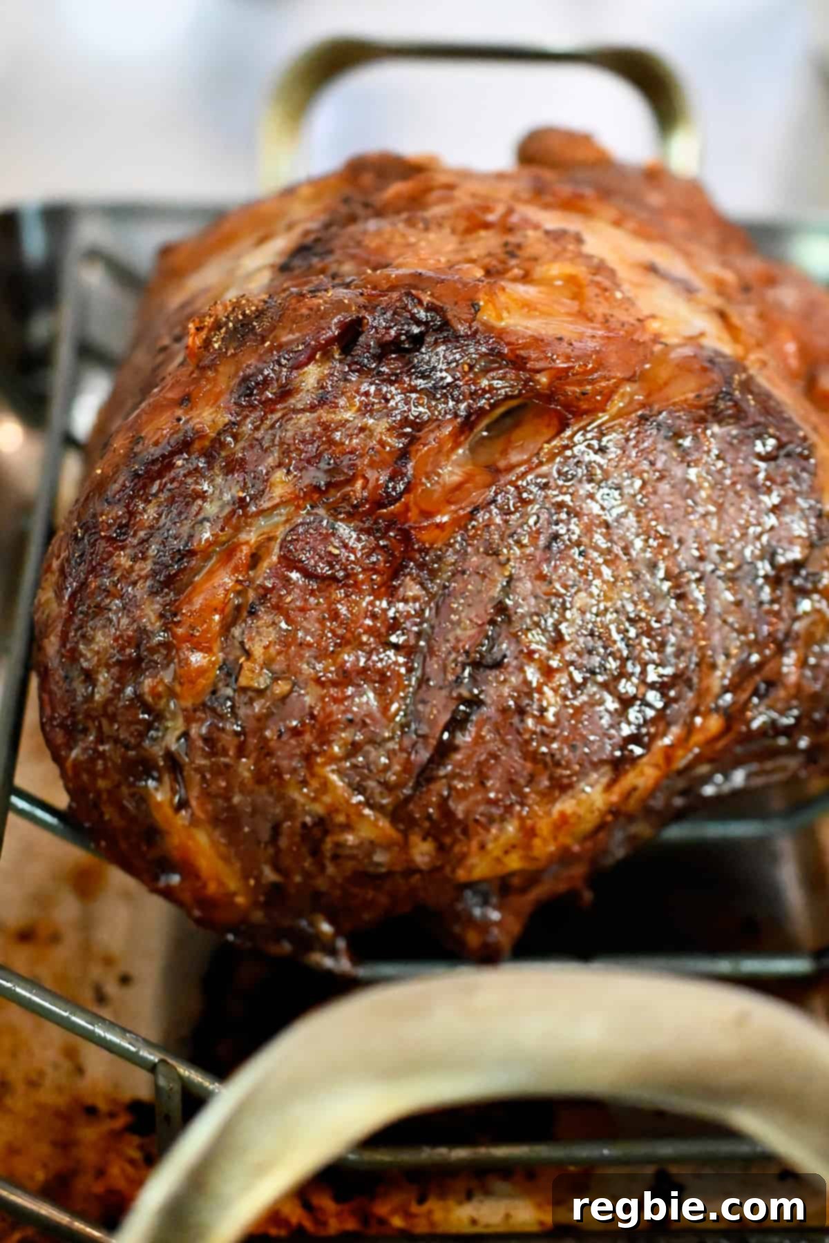 A side view of a perfectly golden brown prime rib roast, showcasing its crispy, seared exterior, resting in a roasting rack.