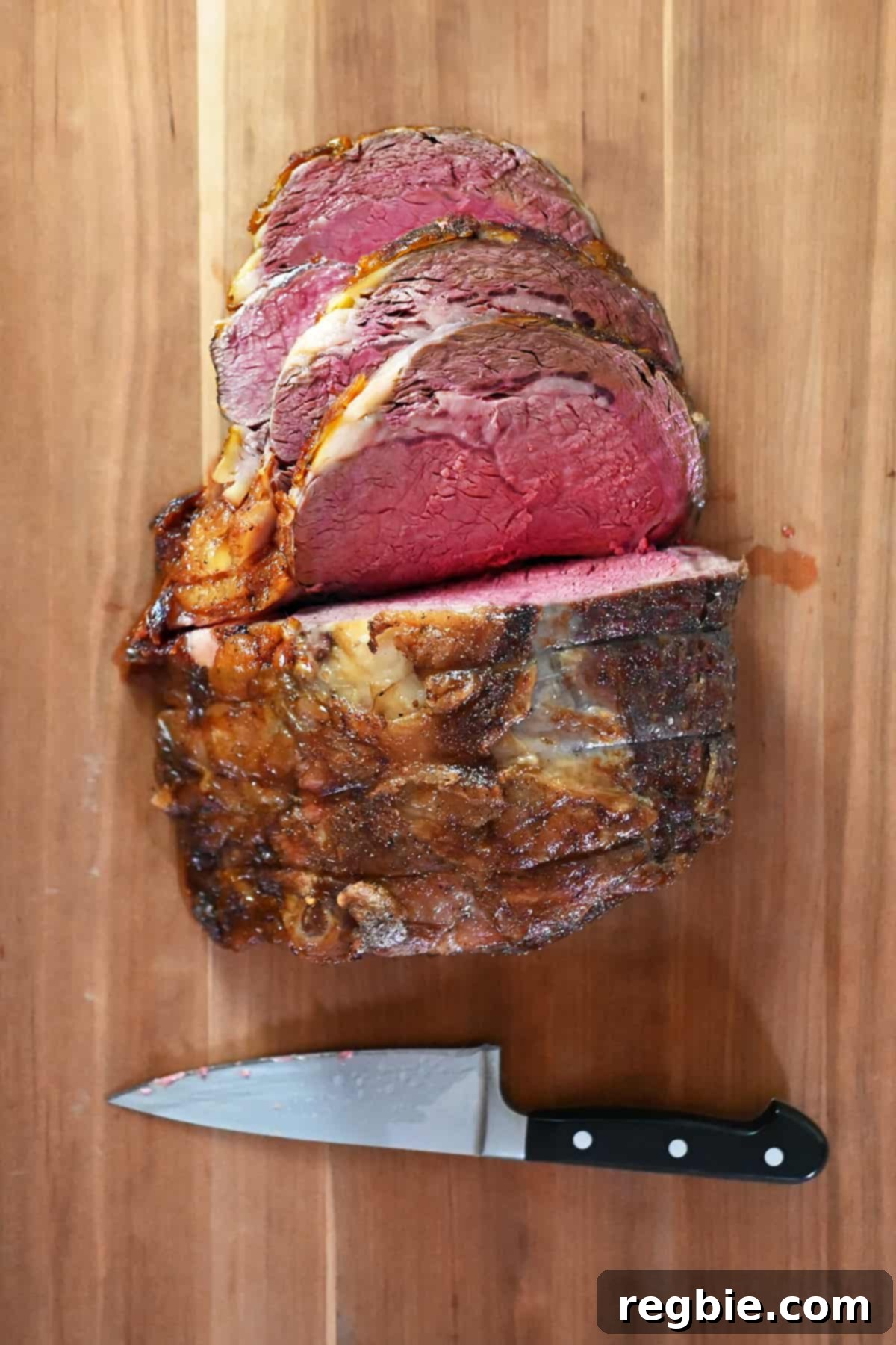 An overhead shot of a medium-rare prime rib roast being expertly sliced on a wooden cutting board, revealing its juicy, pink interior.