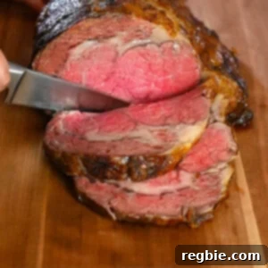 Someone slicing a medium rare prime rib roast on a wooden cutting board.