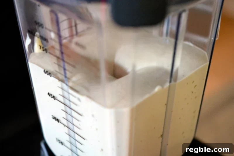 A side shot of a blender filled with creamy Tonnato Sauce, showcasing its smooth and emulsified texture after blending.