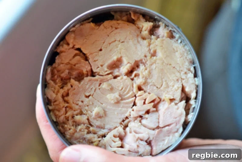 An overhead shot of a can of tuna in olive oil, with the oil expertly drained out, ready for blending.