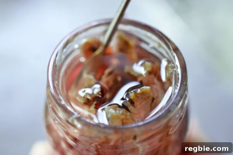 A closeup of an open jar of anchovies in olive oil with a spoon inside, showcasing the savory fillets.