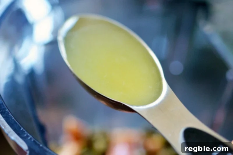 A shot of a spoonful of lemon juice positioned over an open blender container, adding fresh citrus to the Tonnato Sauce ingredients.
