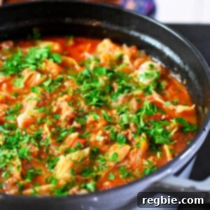 A side view of a gray stockpot filled with paleo and Whole30 cabbage roll soup, garnished with fresh parsley.