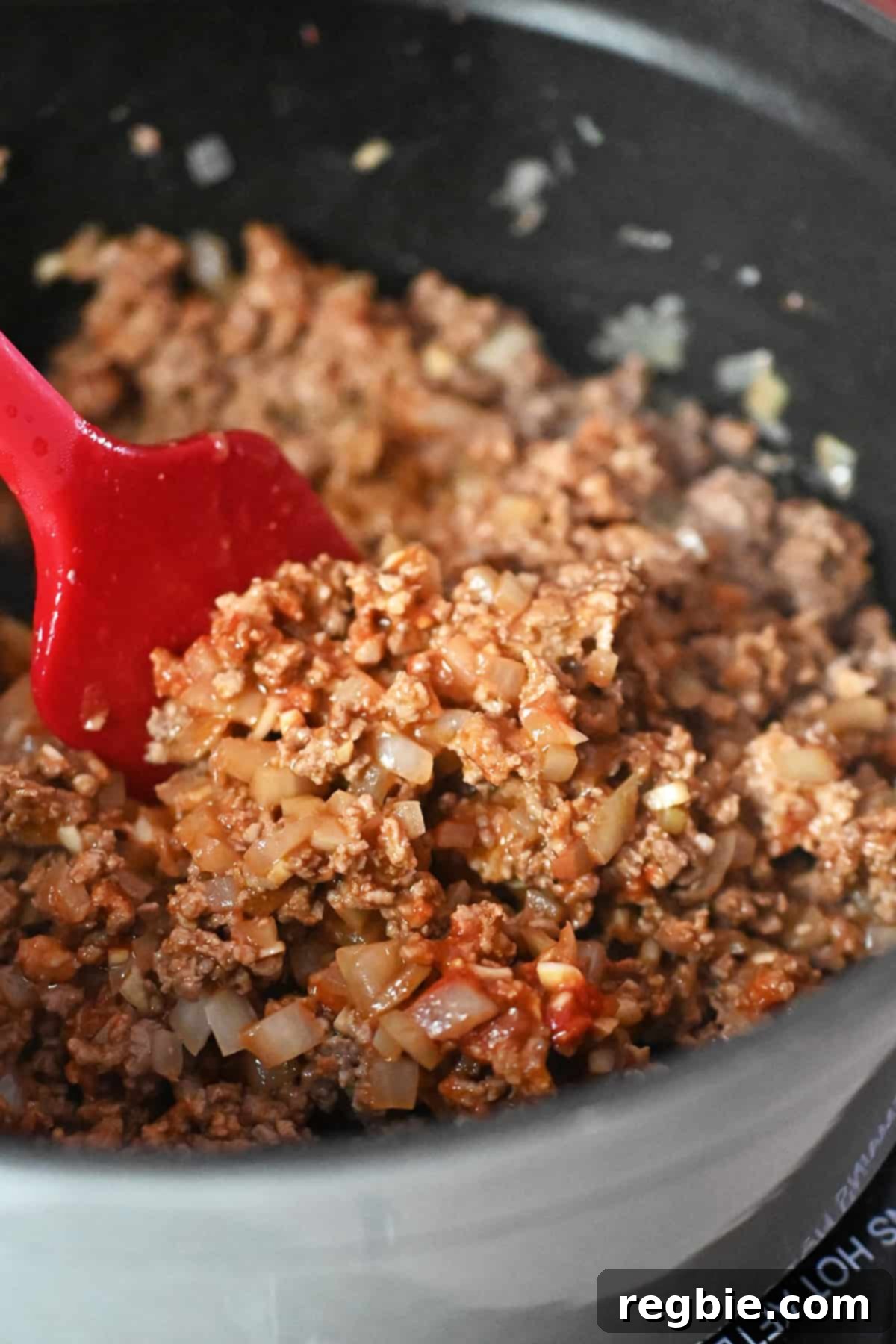 A closeup of seasoned ground meat and onions in a gray stock pot to make cabbage roll soup.