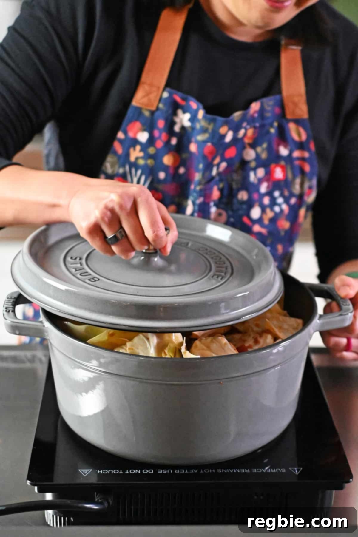 Placing a lid on top of a gray stockpot filled with cabbage roll soup.