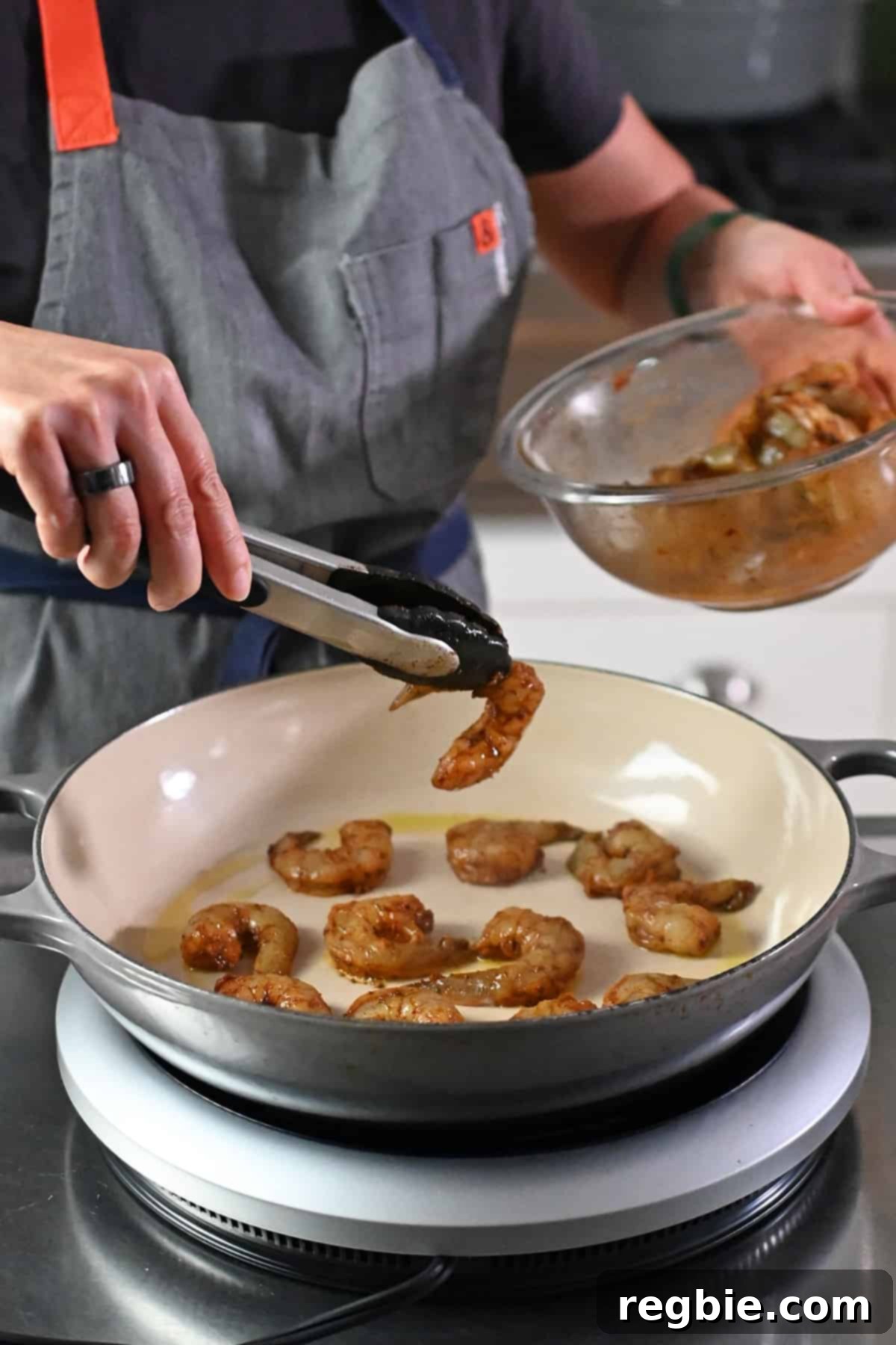 The process of carefully placing raw, seasoned shrimp in a single layer into a hot cast iron skillet, ensuring even cooking for perfect fajitas.
