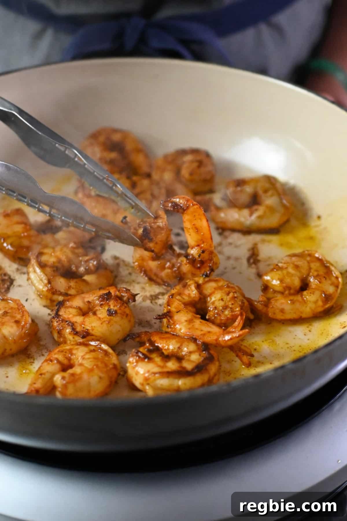 A close-up view of succulent shrimp cooking in a cast iron skillet, showing them turning pink and opaque, a crucial stage in making perfect shrimp fajitas.
