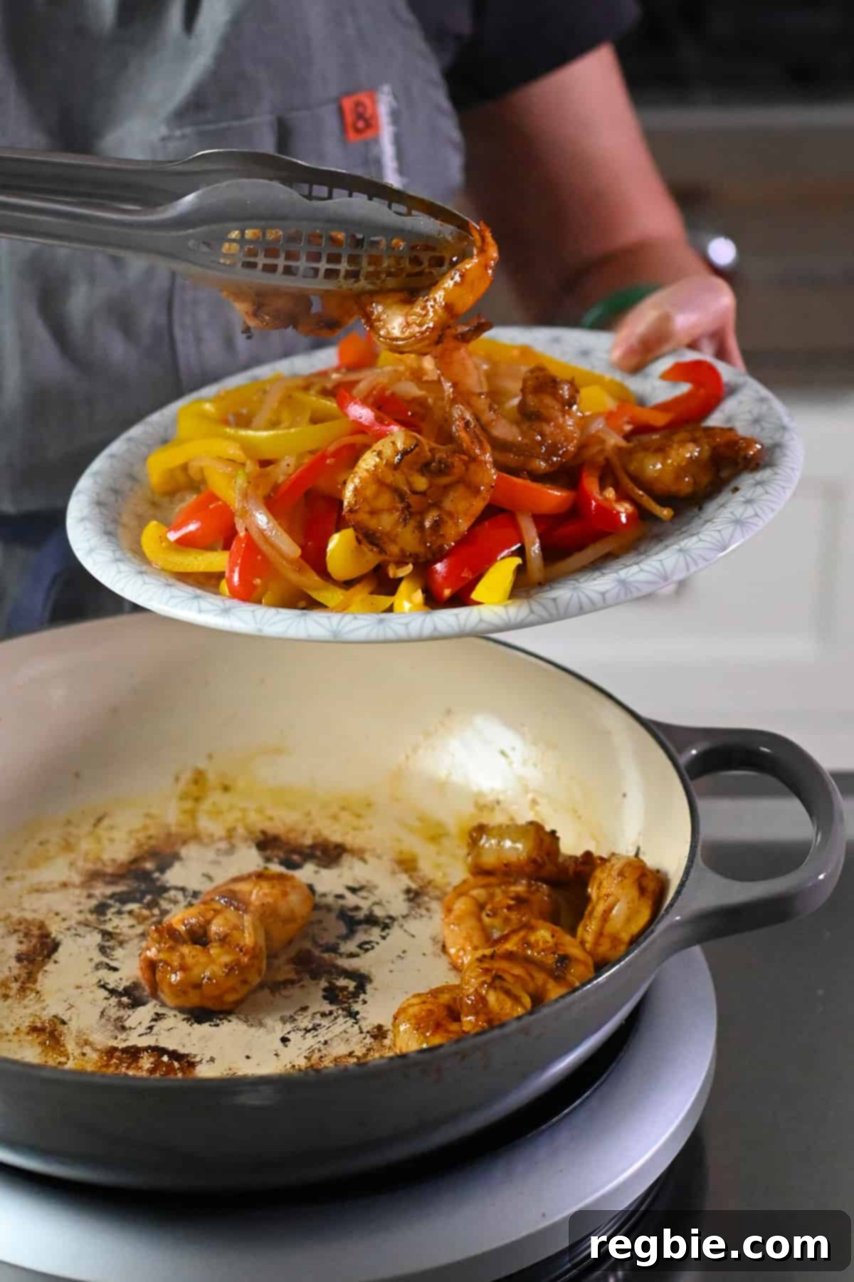 Carefully transferring the perfectly cooked shrimp from the skillet to a plate alongside the already prepared fajita vegetables, ready for the final assembly.